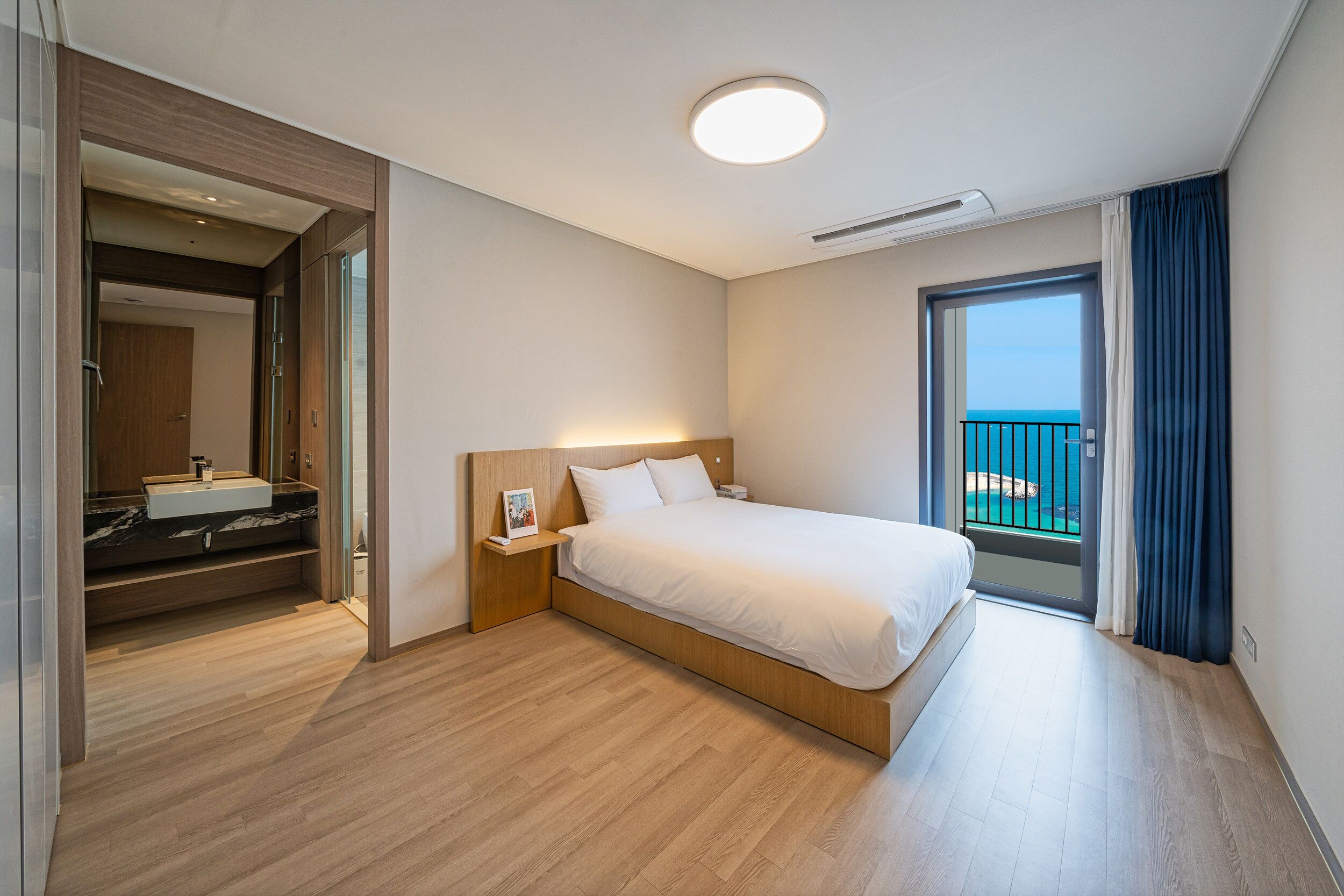 Een moderne hotelkamer met een groot bed, een ingebouwde kaptafel en een balkon met uitzicht.