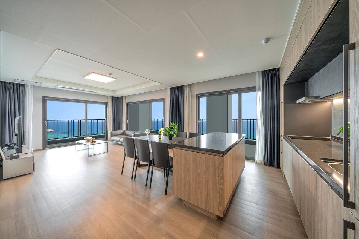 Un apartamento moderno con cocina, comedor y balcón con vista al mar.