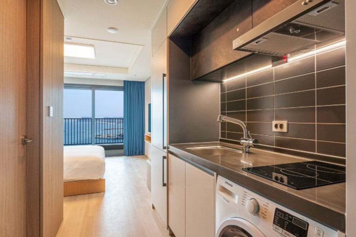 Une cuisine moderne dotée d’un lave-linge encastré, d’une grande fenêtre et d’un balcon avec vue.