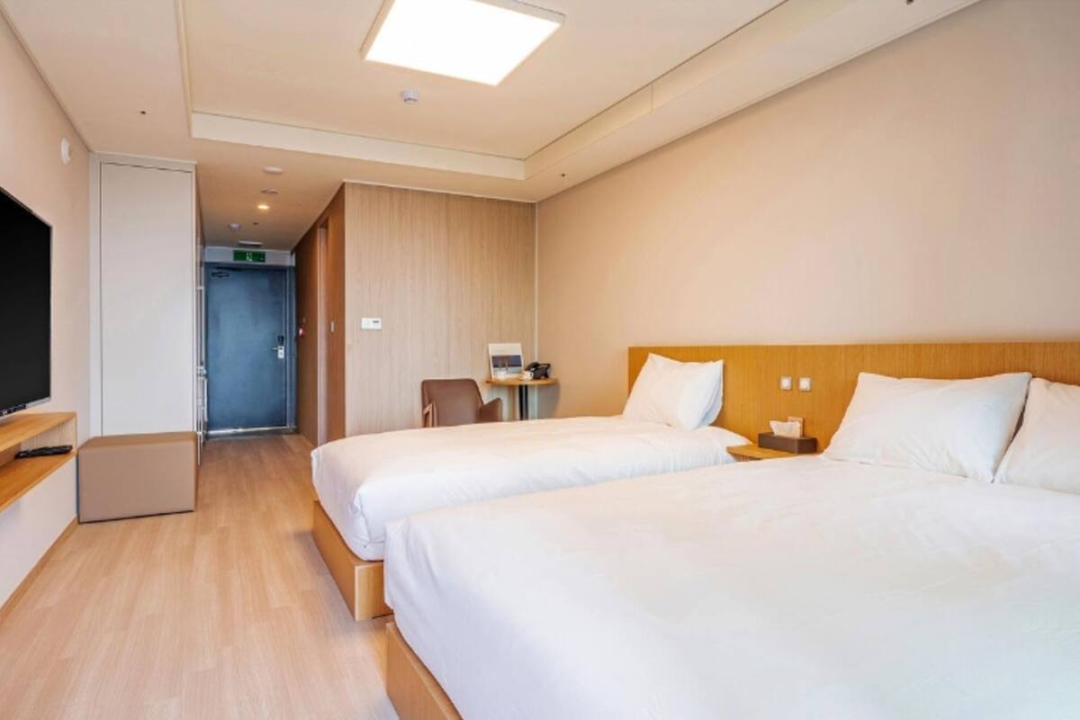 Una habitación de hotel con dos camas, televisión, escritorio y una silla.