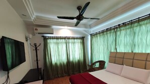 A hotel room with a bed, a TV, a ceiling fan, and a window with curtains. - Darul Salam Orkid Inn (Kerteh)