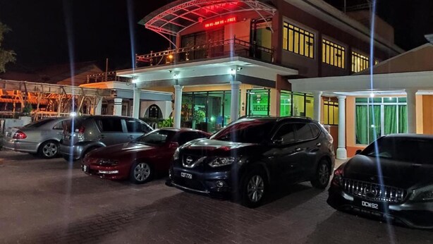 A hotel with a covered entrance, multiple cars parked in front, and a flag on top. - Darul Salam Orkid Inn (Kerteh)