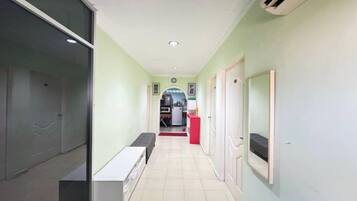 A hallway with a bench, a door, and a mirror on the wall.