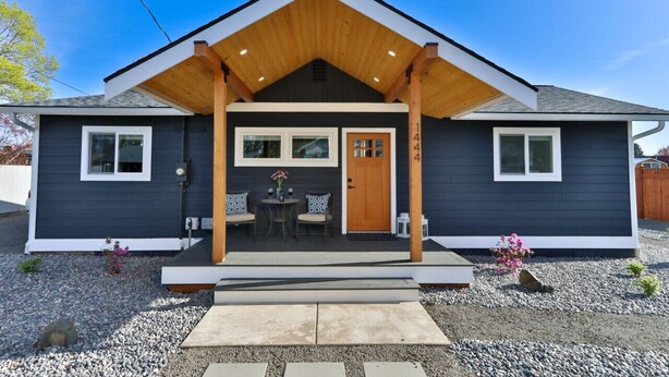 Een modern huis met een donkere gevel, een houten veranda en een klein terras.