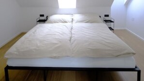 Un dormitorio con cama, tragaluz y ventana.