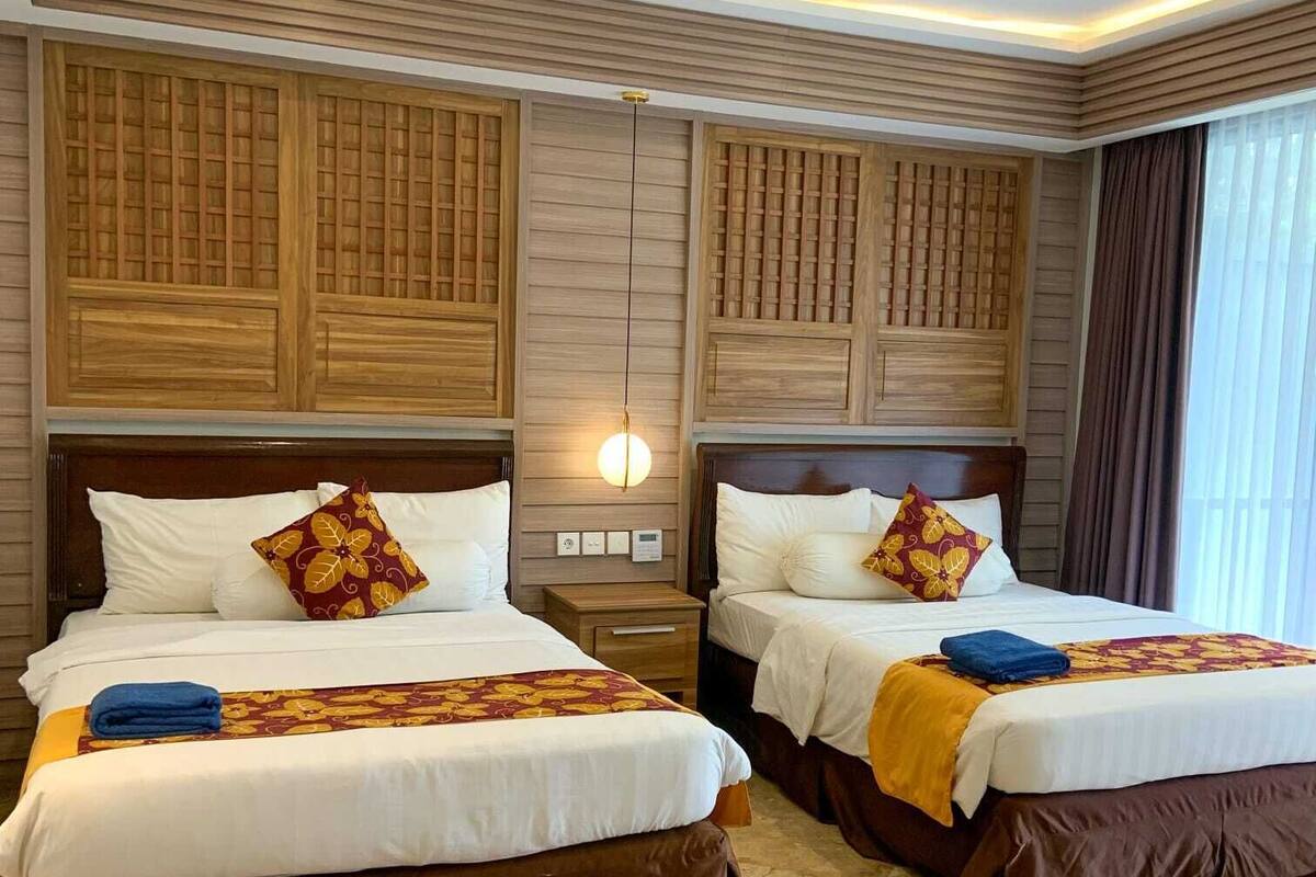 Ein Hotelzimmer mit zwei Betten, Holz-Kopfteilen und einem modernen Deckenstil.
