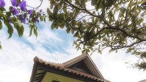 A two-story house with a covered porch and a small garden area with purple flowers. - lorin beach resort belitung (Tanjung Pandan)