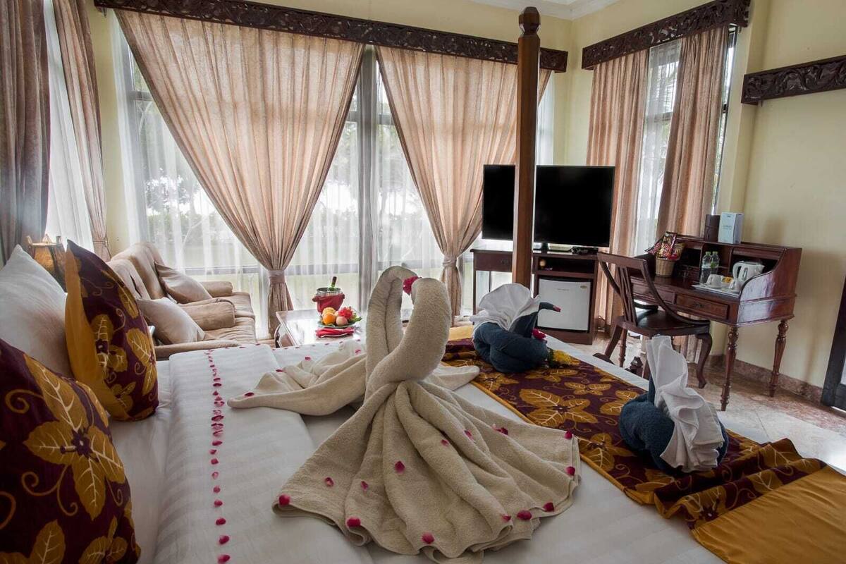 Ein Hotelzimmer mit einem großen Bett, einem Schreibtisch, einem Fernseher und Blick ins Freie.