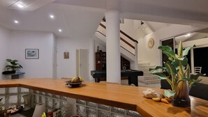 Ein modernes Wohnzimmer mit einem Holzbüro, einem Billardtisch und einer Treppe zu einer oberen Ebene.