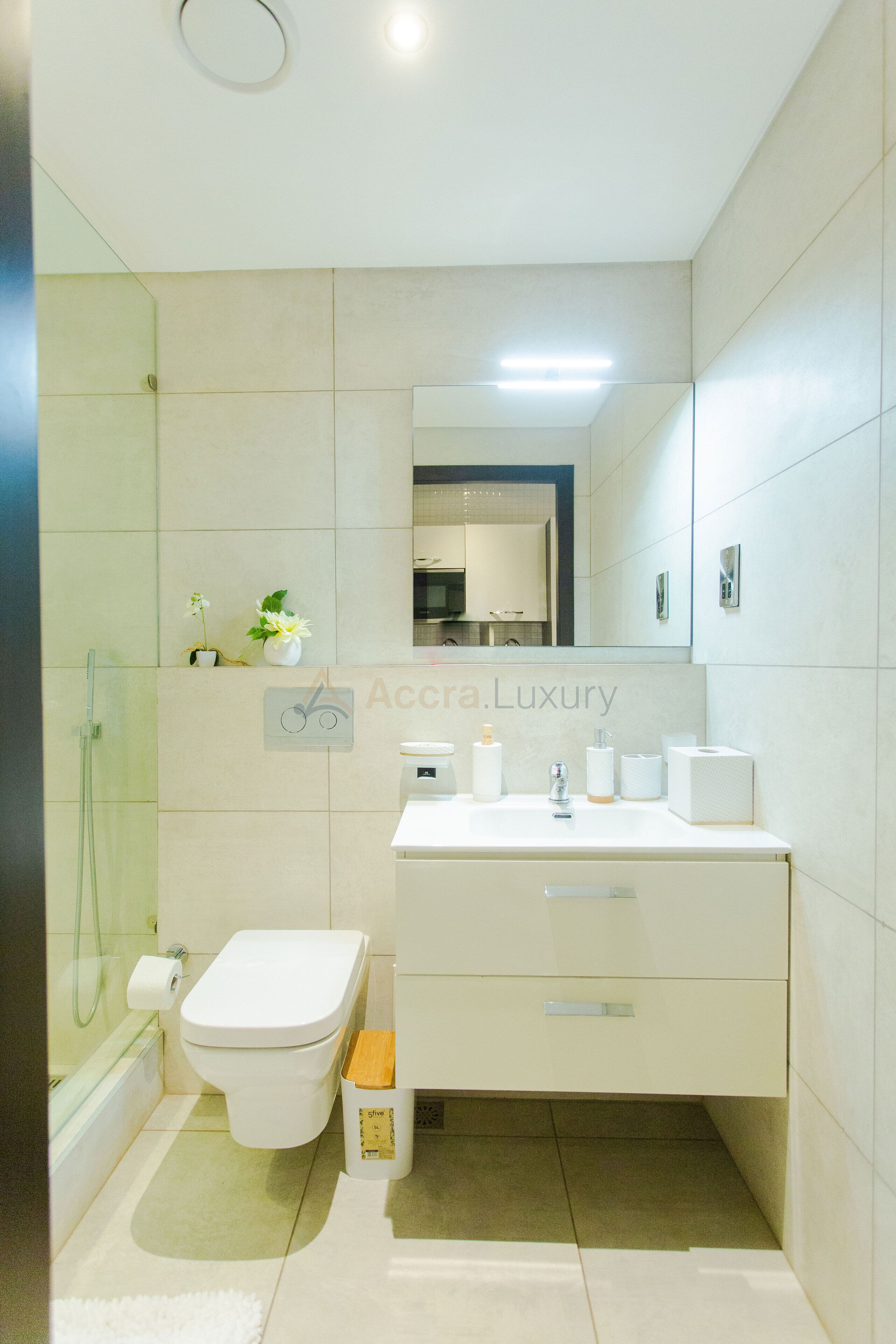 A modern bathroom with a toilet, sink, and shower.