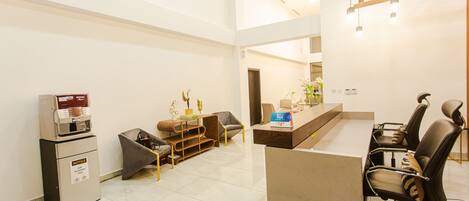 A modern reception area with a counter, seating, and a small refrigerator.