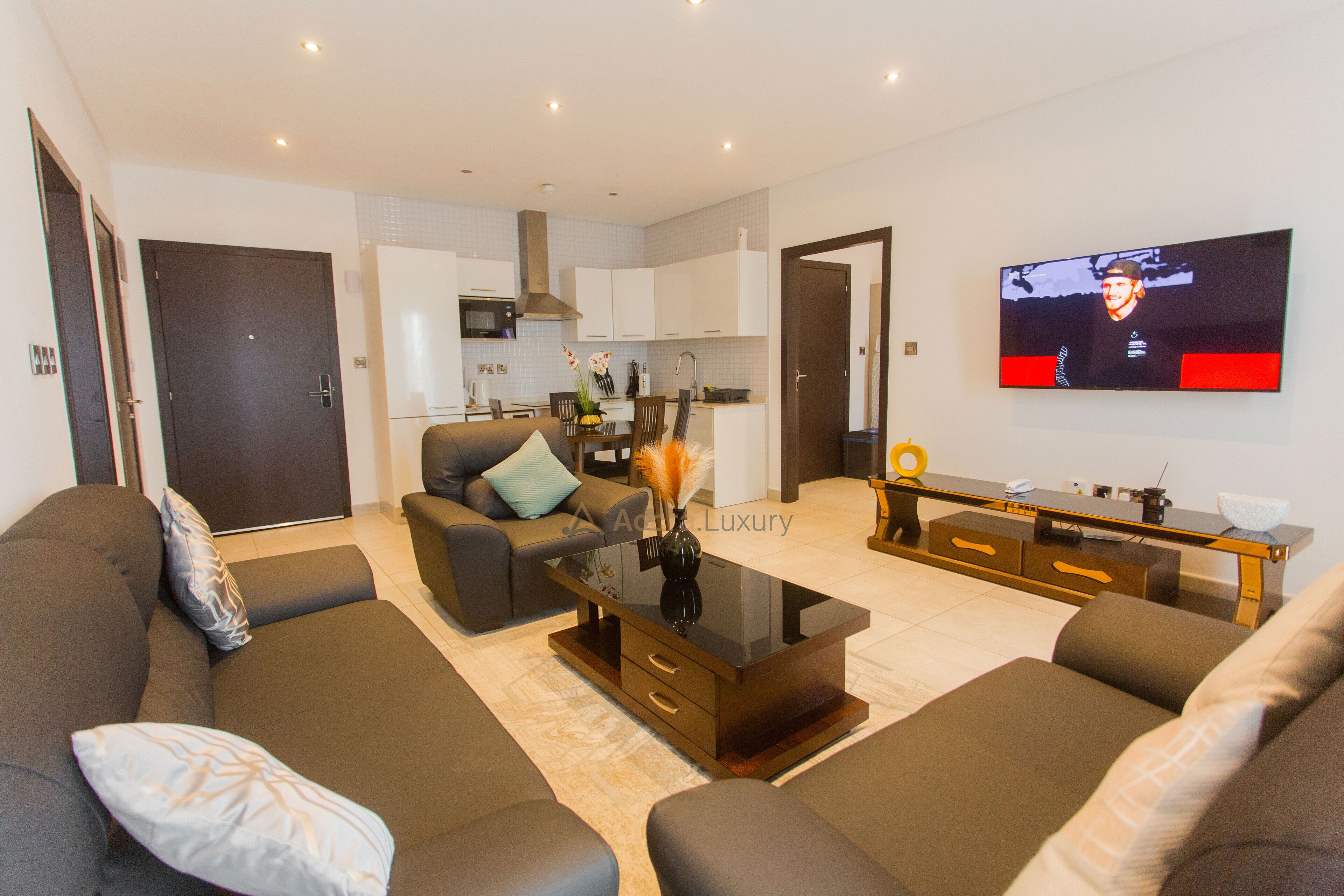 A modern living room with a sofa set, a coffee table, and a TV mounted on the wall.