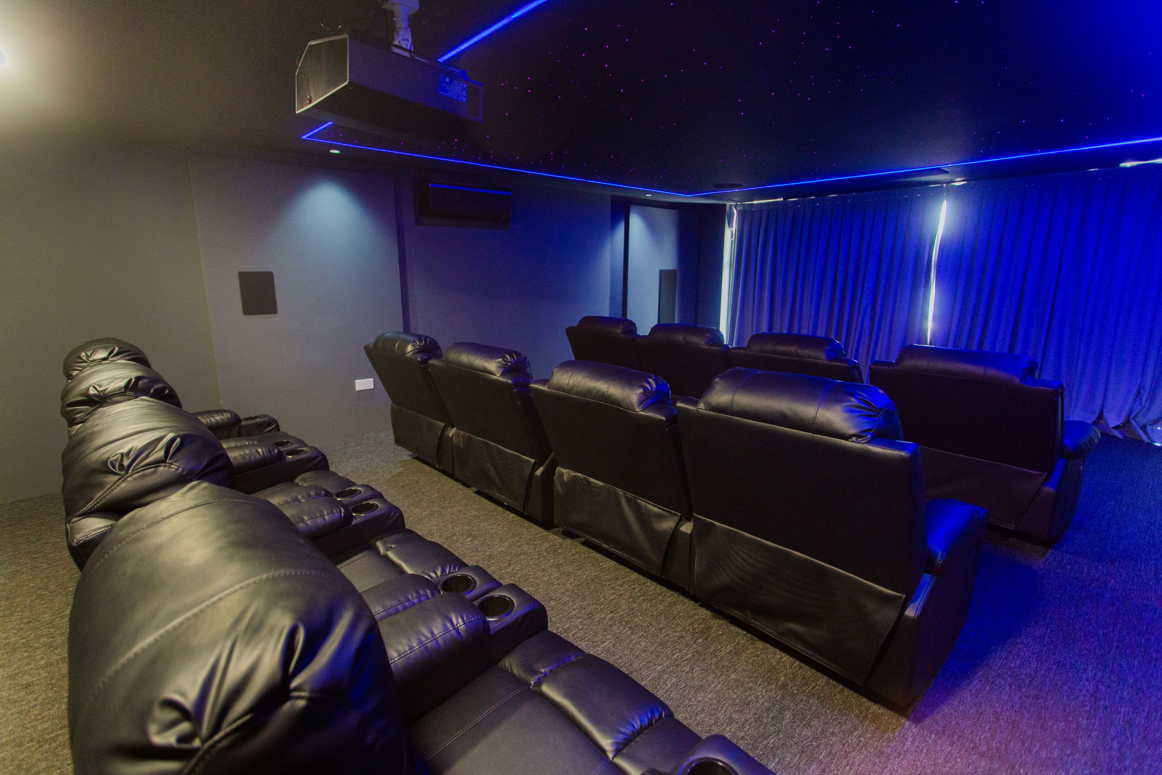 A home theater with leather reclining seats and a starry ceiling.
