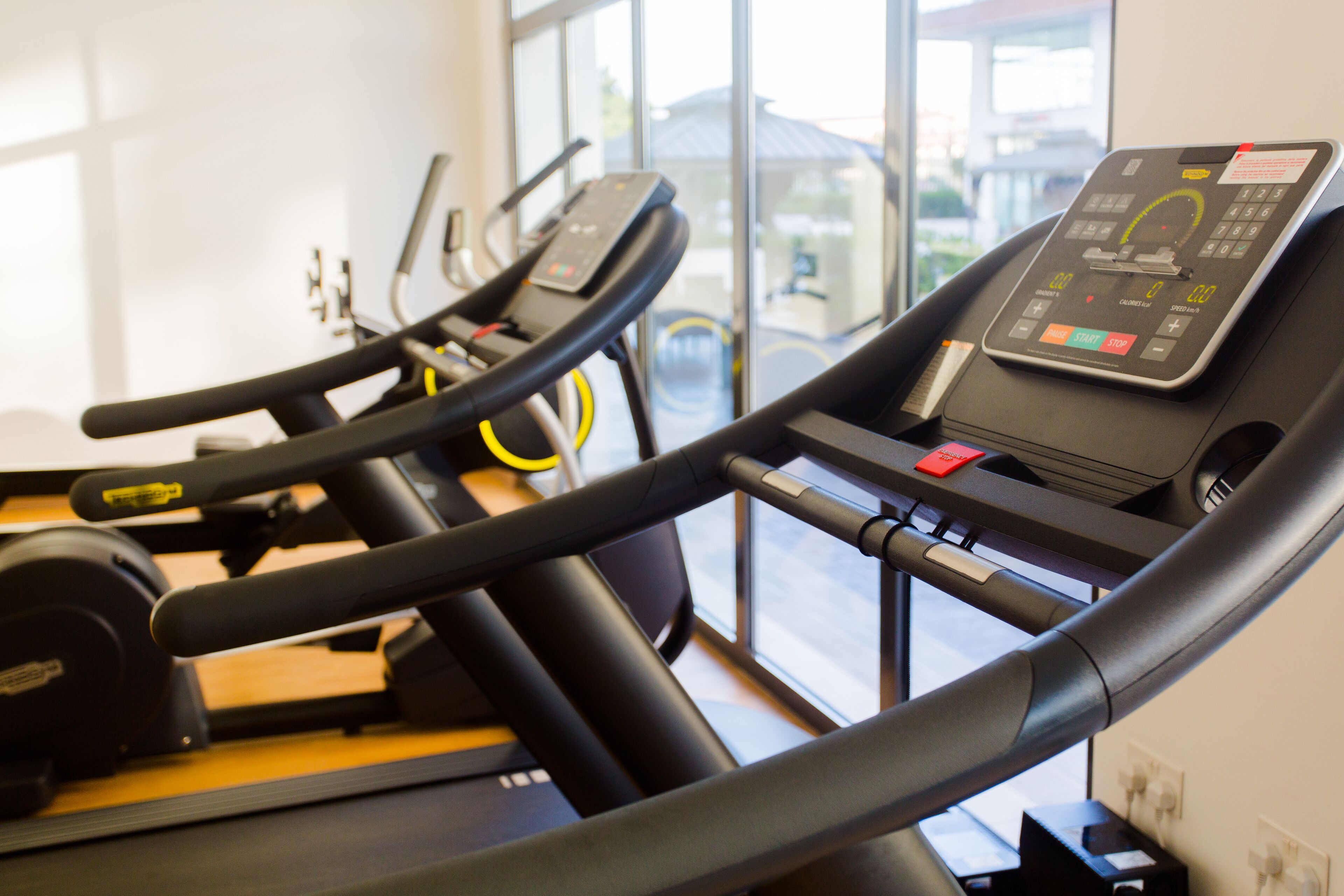 A row of stationary bikes in a gym with a control panel on the right.