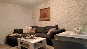 Un salon avec un mur en pierre, un canapé, une table basse et un tableau.