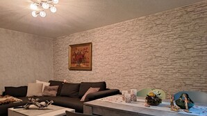 Un salon avec un mur en pierre, un canapé, une table basse et une table à manger avec des chaises.