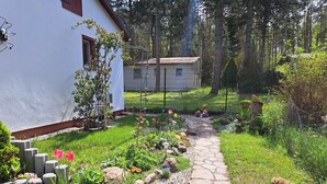 Un chemin de jardin mène à un bâtiment blanc dont les fenêtres sont bordées de rouge.