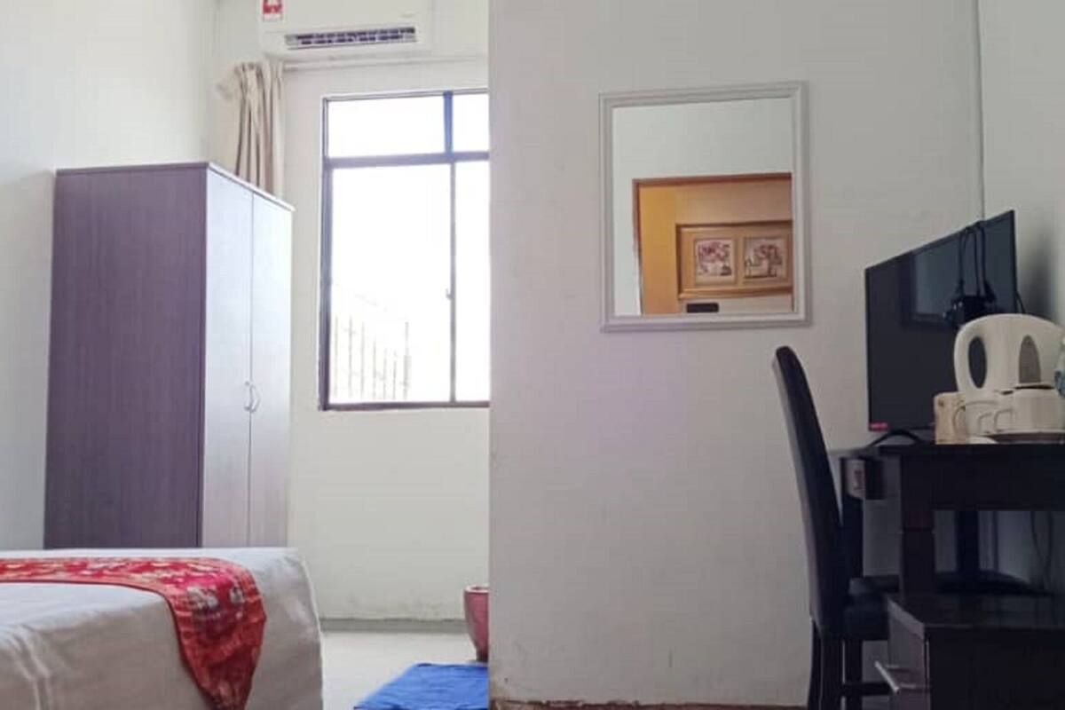 Ein Schlafzimmer mit einem Bett, einem Schreibtisch, einem Sessel, einem Fernseher und einem Fenster.