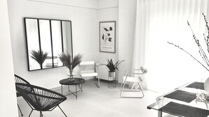 Un salón moderno con un sofá, sillas, una mesa de centro y una mesa de comedor. Hay plantas en macetas y obras de arte en las paredes.