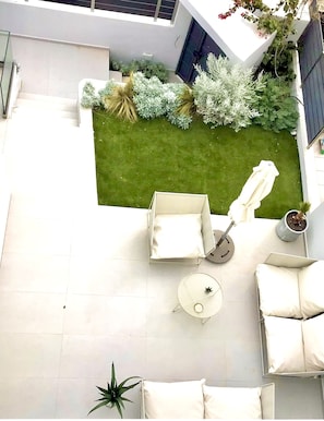A modern patio with a white sofa set, a small round table, and a potted plant.
