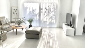 Una sala de estar moderna con sofá, mesa de centro, reposapiés y mueble para televisión.