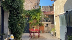 Une cour avec une table et des chaises rouges, entourée de bâtiments et de verdure.