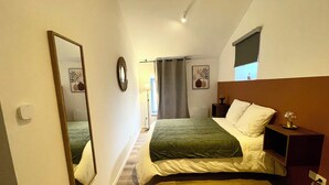 Une chambre à coucher avec un lit, une table de chevet, un miroir et une fenêtre.