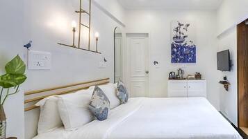 Un dormitorio con cama, mesita de noche y televisor empotrado en la pared.