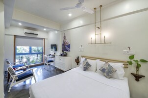 Habitación de hotel con cama, escritorio, silla y vistas a zonas verdes.