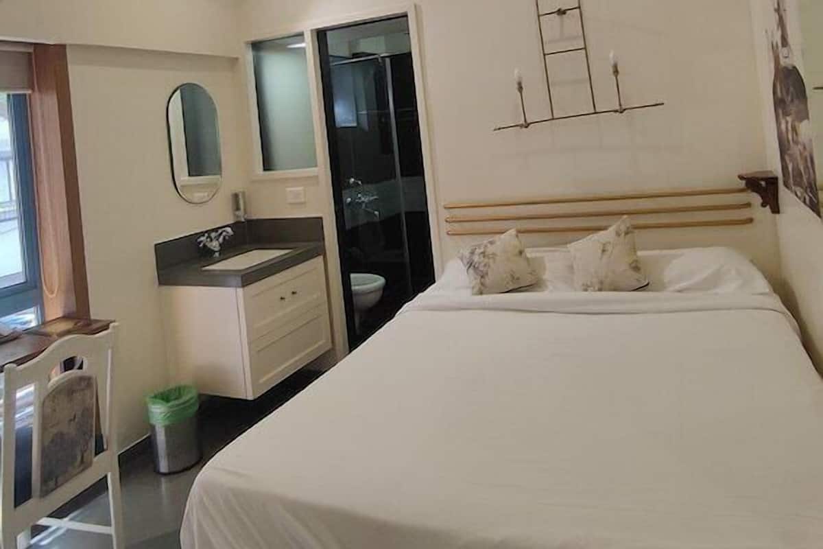 A hotel room with a bed, a vanity with a mirror, a small desk, and a closet.