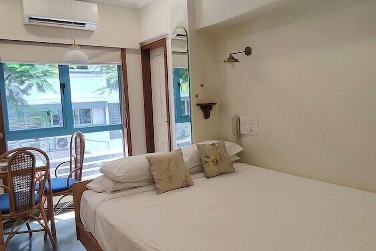 A bedroom with a bed, a ceiling fan, a window with a view, and a chair.