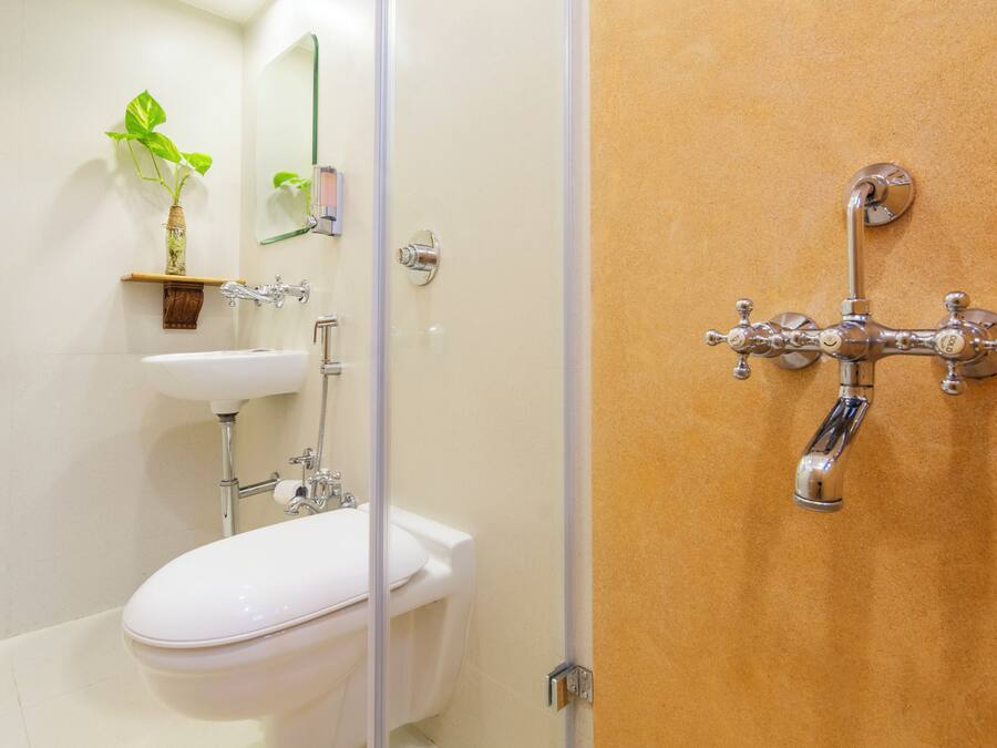 Un baño con inodoro blanco, lavamanos y ducha con grifo cromado.