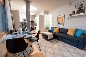 Un salon moderne avec un coin repas, un canapé et une cuisine en arriÚre-plan.