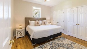 Une chambre à coucher avec un lit, une table de chevet, un ventilateur de plafond et des portes blanches.