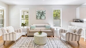 Un salon moderne avec un canapé, deux fauteuils, une table basse et un tableau accroché au mur.