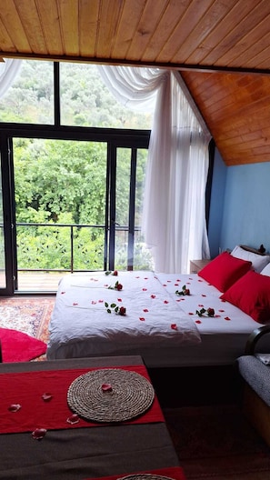 A bedroom with a large bed, a view of greenery outside, and a wooden ceiling. - Ahsen Pansiyon (Selçuk)