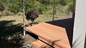 Un espacio de estar al aire libre cubierto con bancos de madera y vistas a un paisaje montañoso.