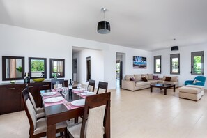 A spacious living area with a dining table, sofas, and a TV.