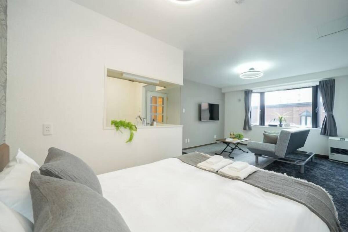 Habitación de hotel con una cama grande, un escritorio, una silla, un televisor y una ventana con cortinas.