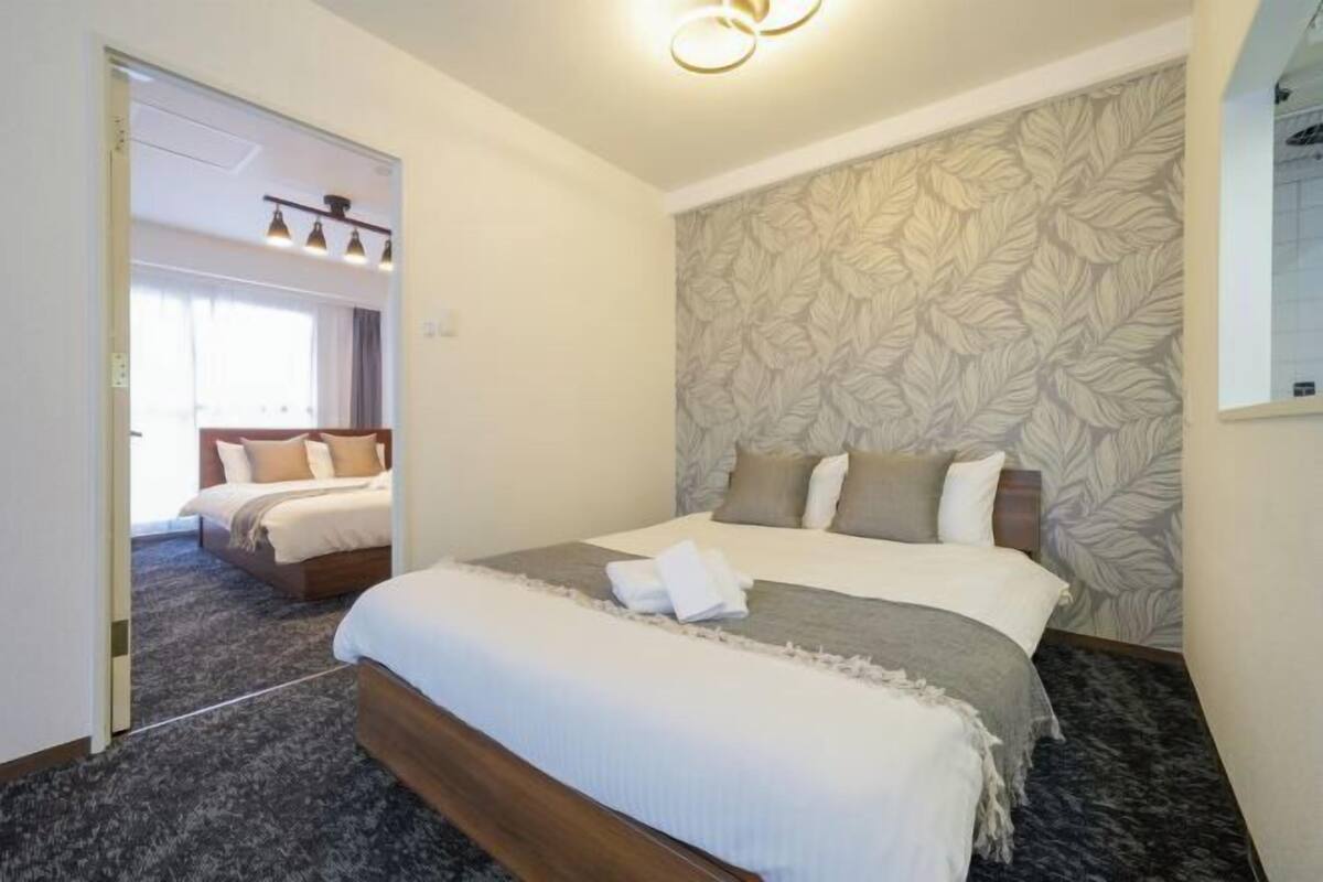 Habitación de hotel con una cama grande, papel tapiz estampado y una lámpara en el techo.