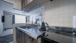 Eine moderne Küche mit Spüle aus Edelstahl, Holzschränken und einem schwarzen Wasserkocher.