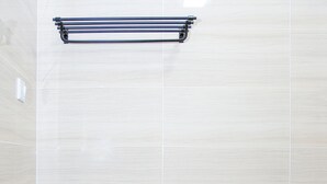 Une salle de bain équipée de toilettes, d’un porte-serviettes et d’un flexible de douche.