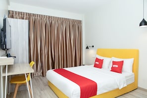 Une chambre d’hôtel avec un lit, un bureau, une chaise, une télévision et des rideaux.