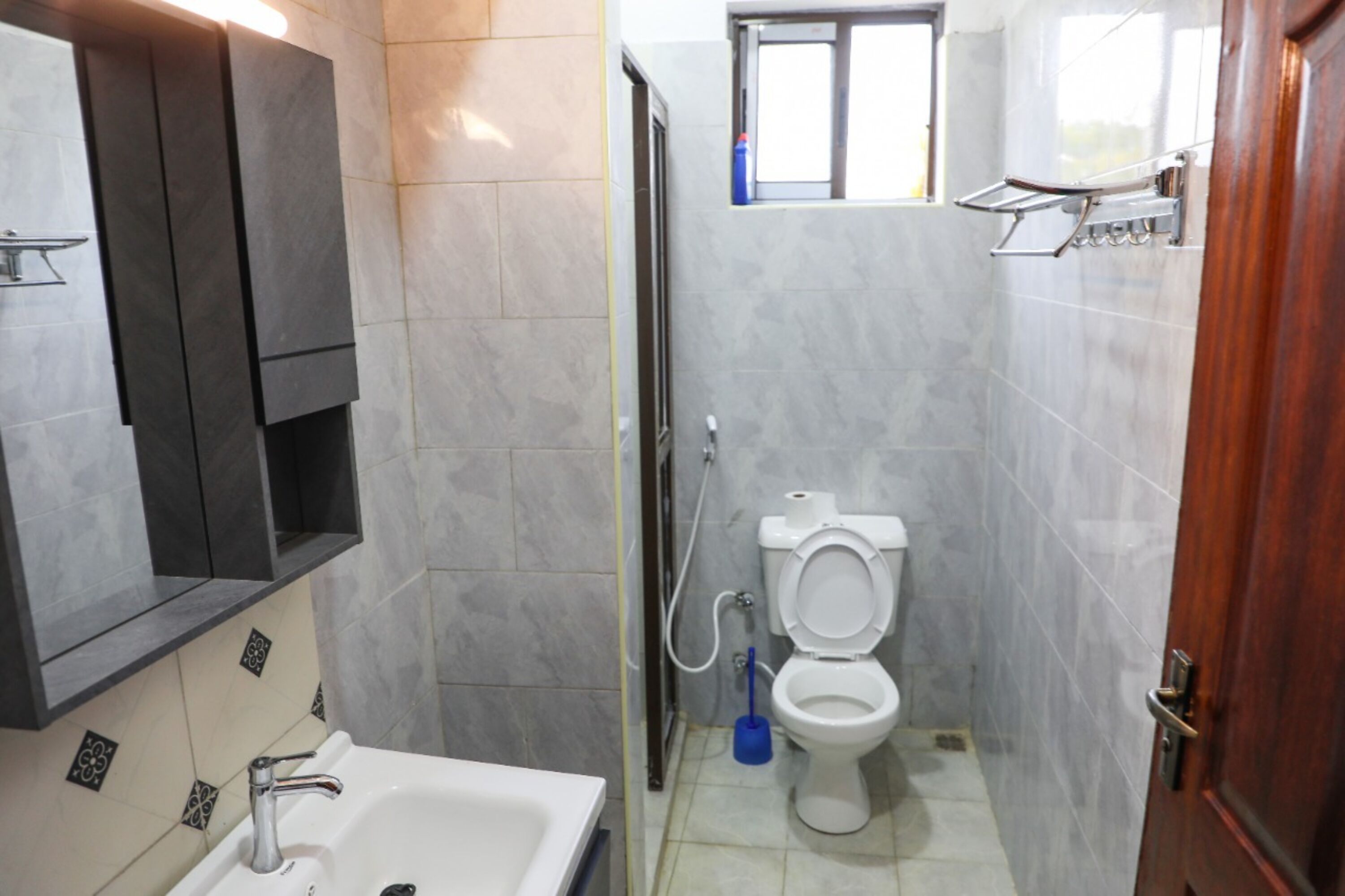 Egy fürdőszoba, amelyben mosdókagyló, WC és zuhanyzó található.