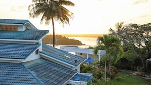 A multi-story building with a blue-tiled roof, surrounded by lush greenery and palm trees. - Kilifi Blue House Resort (Kilifi)