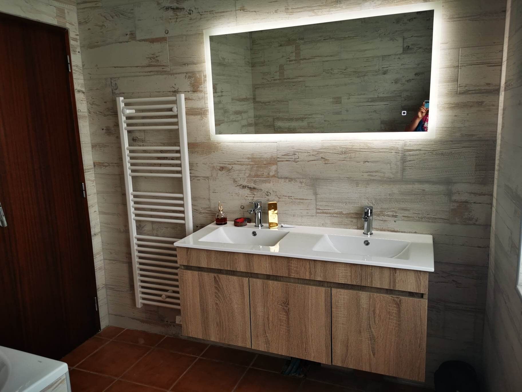 A bathroom with a wooden vanity, two sinks, a towel rack, and a mirror above the vanity.