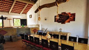 A rustic dining area with a long table, red cushioned chairs, and a hanging light fixture. - Maison de Campagne au Calme (Ventosa)