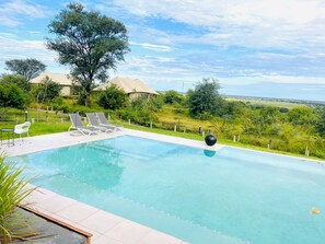 Una piscina al aire libre, sombrillas, tumbonas