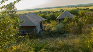 Deux huttes aux toits de chaume, situées dans un cadre naturel et offrant une vue sur le paysage.