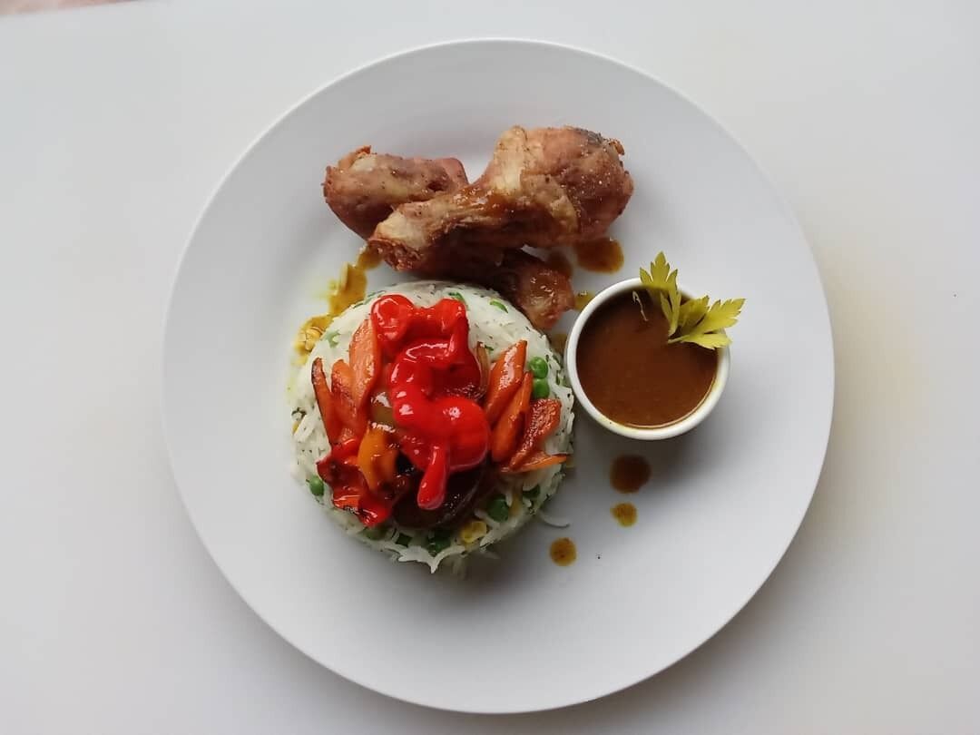 A plate with fried chicken, a salad, and a small bowl of sauce.
